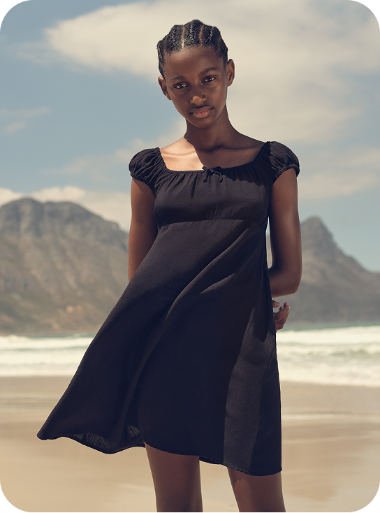 Young girl wearing a black dress on the beach